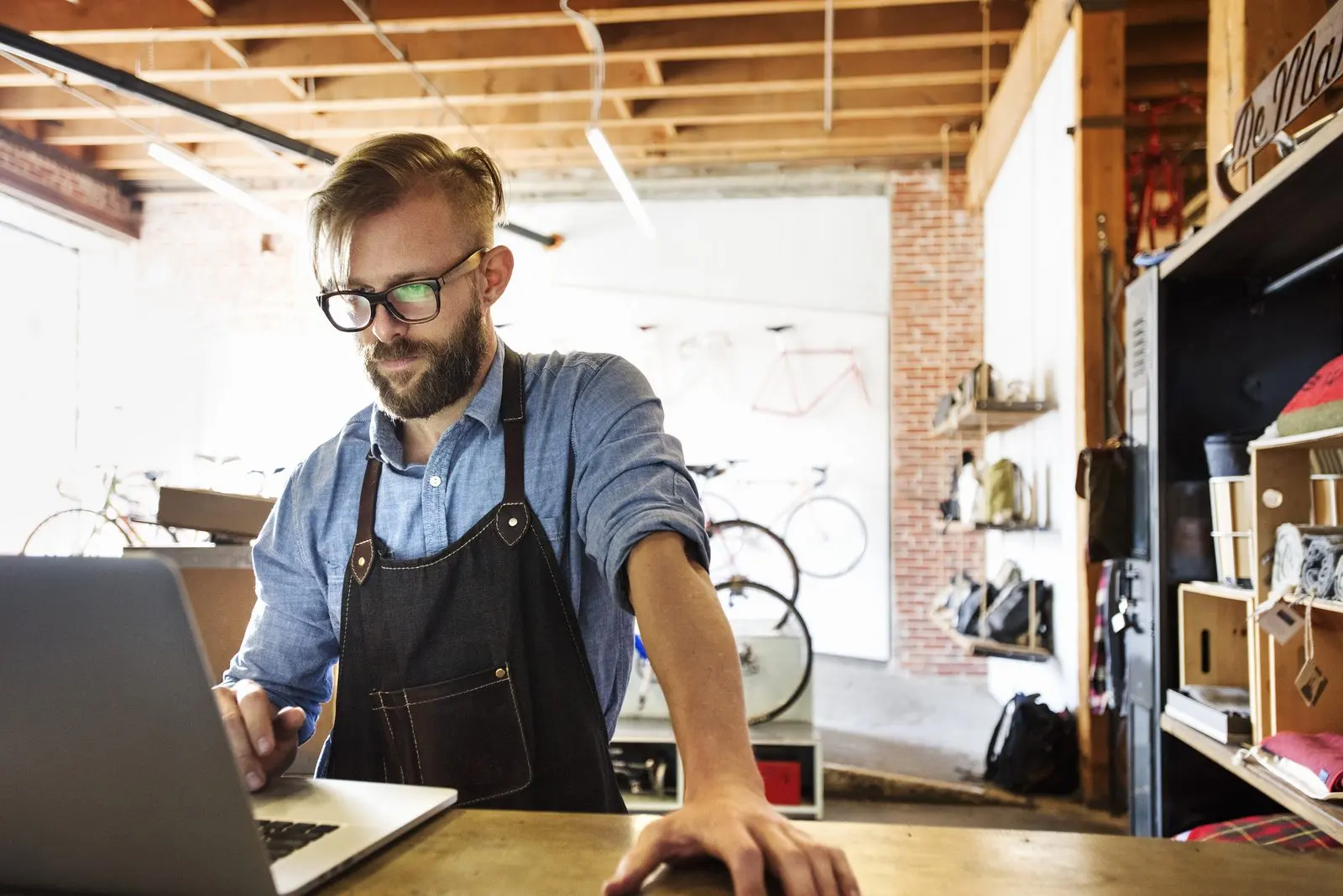 Small business owner checking website data on a laptop in his bike shop