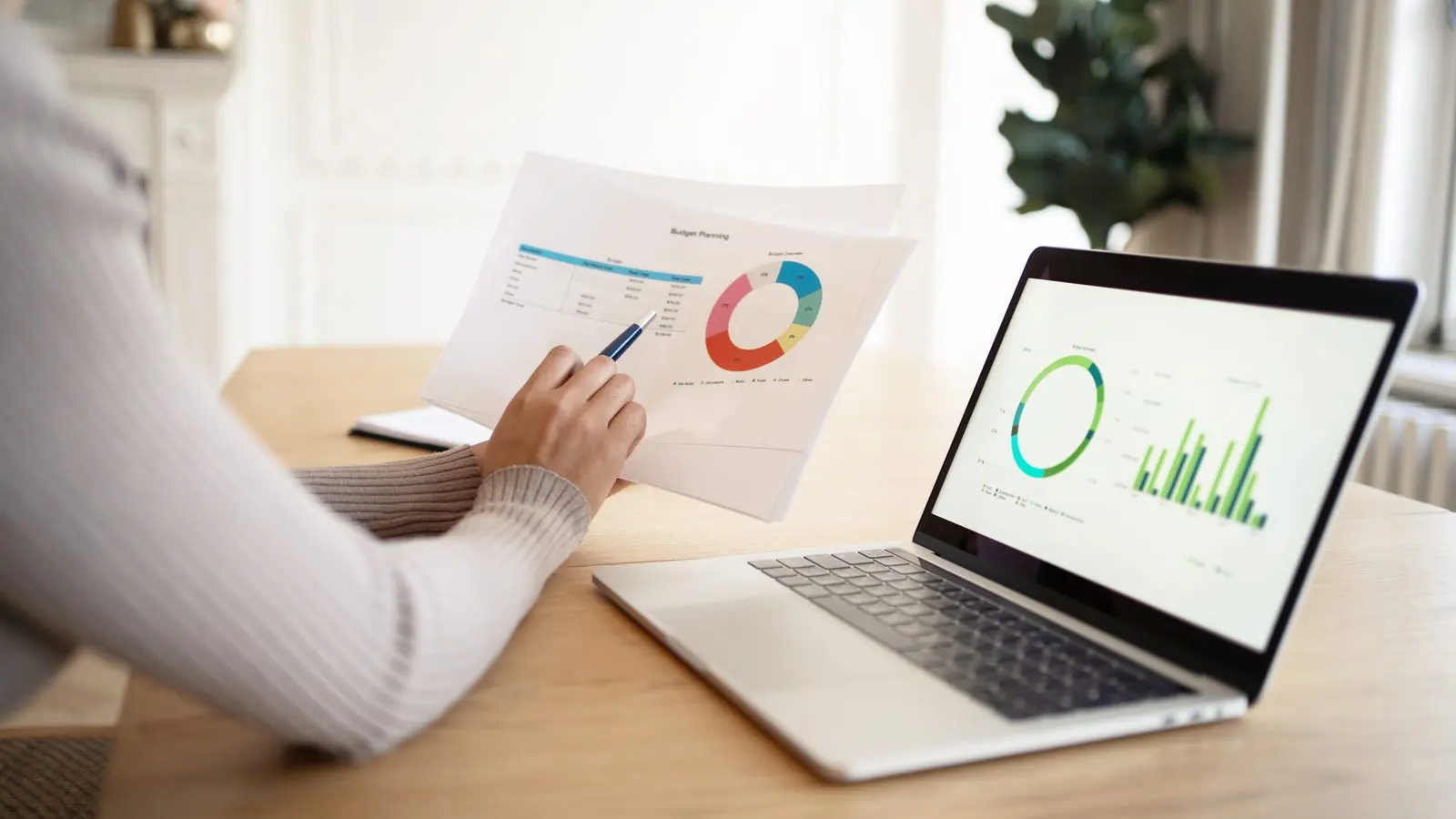 Woman reviewing analytics charts on a laptop and printed reports